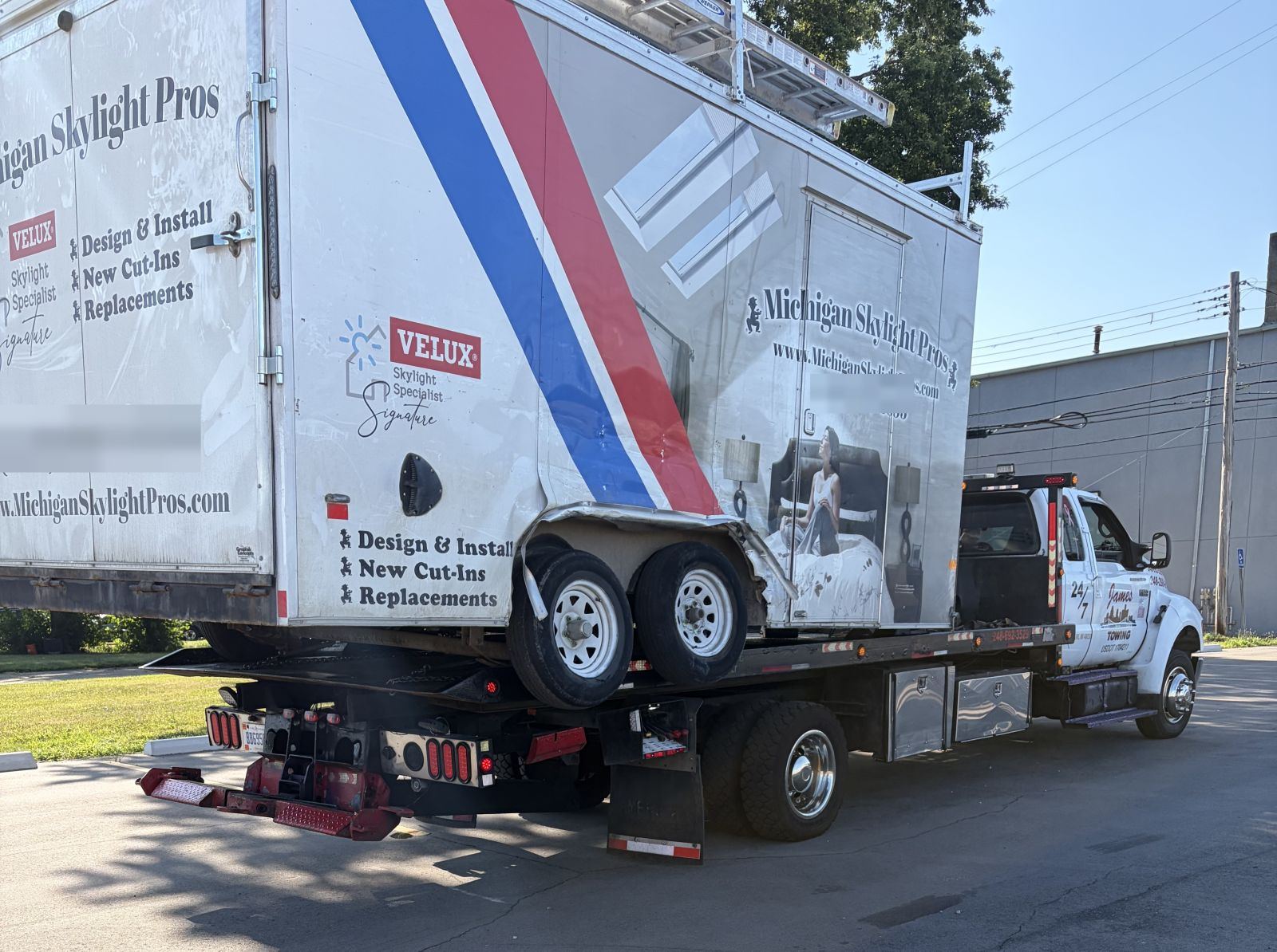 James Towing flatbed hauling a damaged commercial box truck